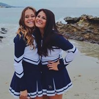 Image of two college age cheerleaders in blue and white uniforms